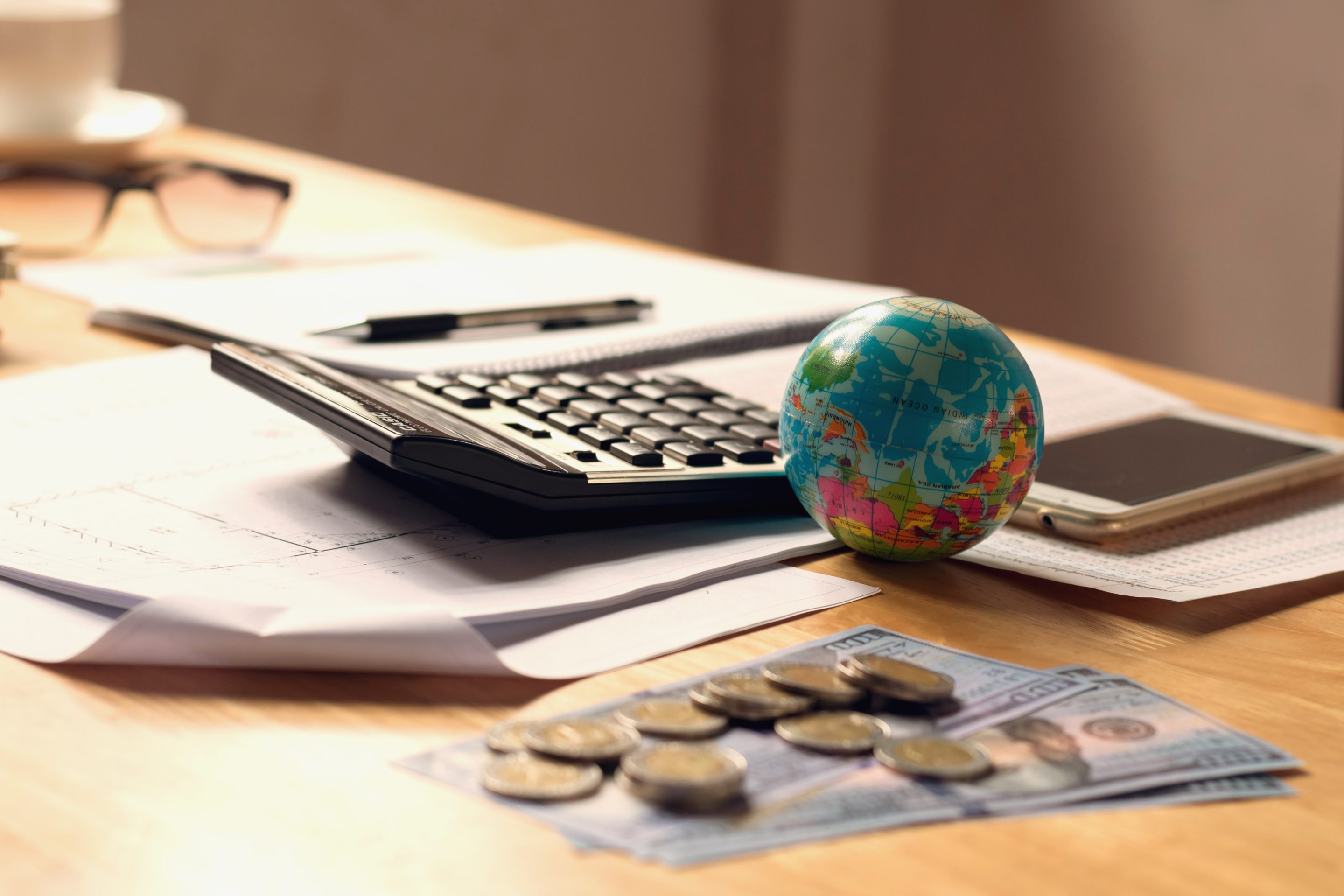 close-up-globe-toy-with-calculator-money-desk-office-accounting-finance-concept